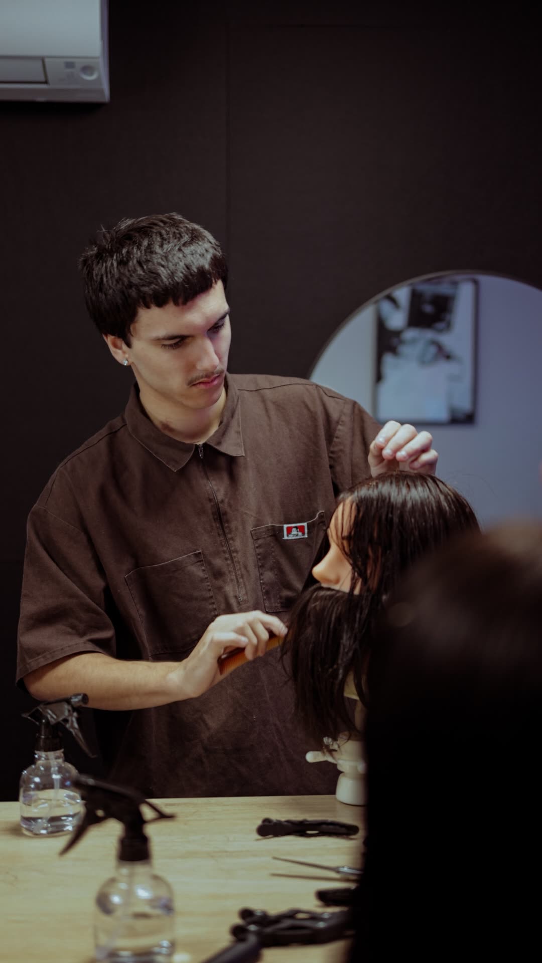 A young man focused on combing through a practice mannequin